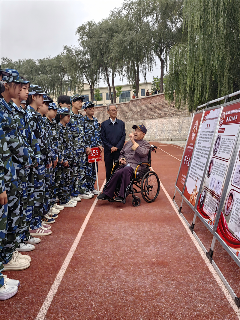 图片为王艾甫正在向青少年开展爱国主义教育