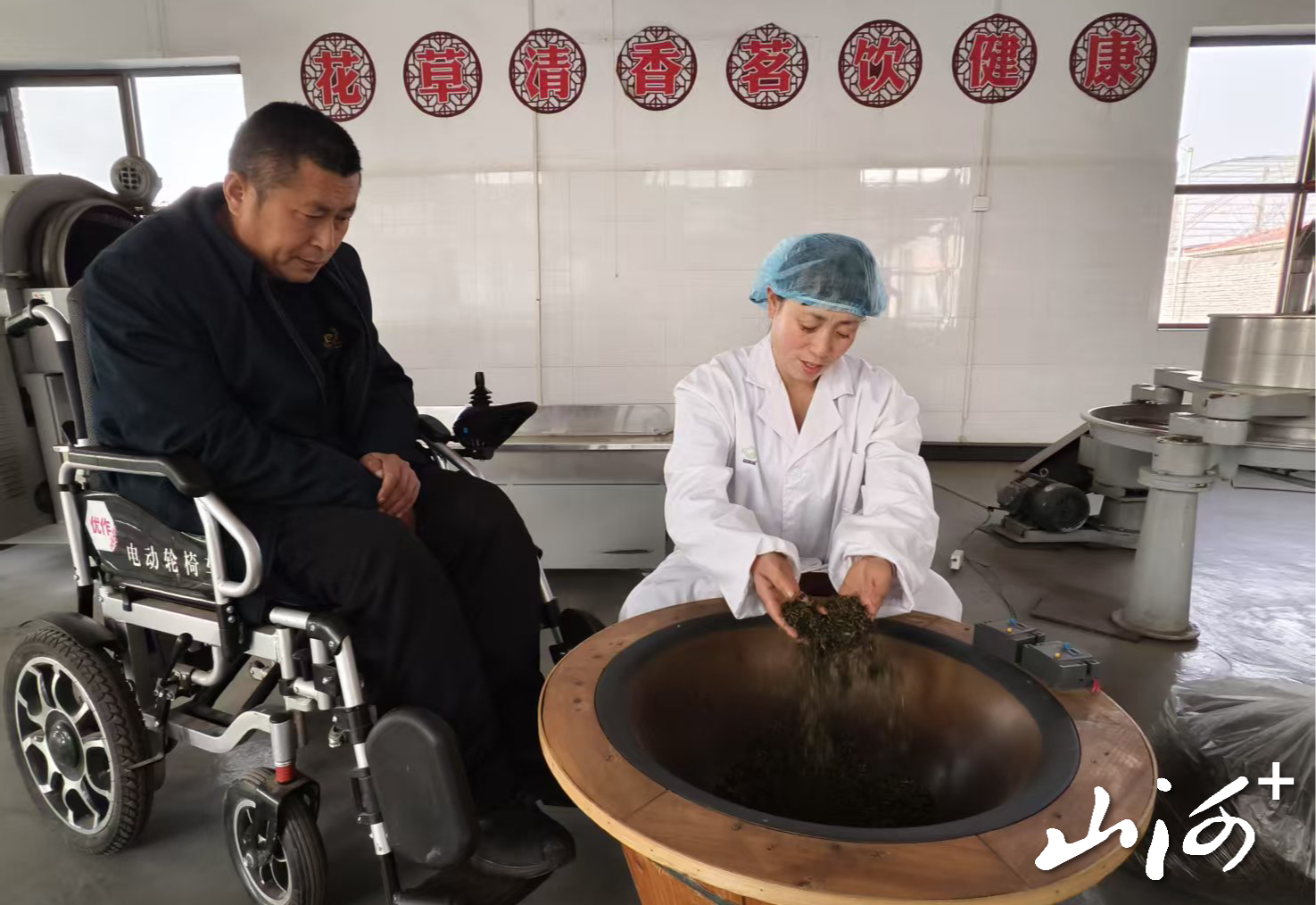 刘俊红正在炒茶，丈夫在一旁陪着